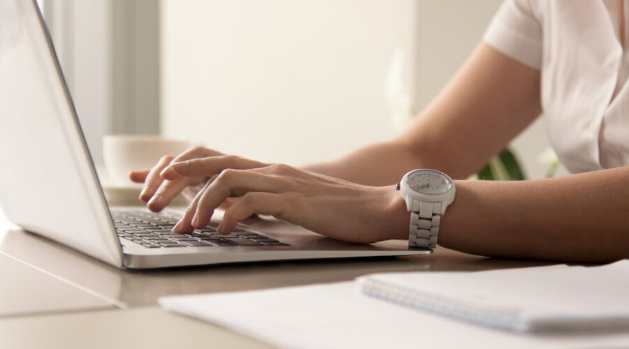 Close up image of womans hands typing on laptop at workplace. Businesswoman with white wristwatch on hand working on computer in office. Female office worker, programmer, entrepreneur searching online